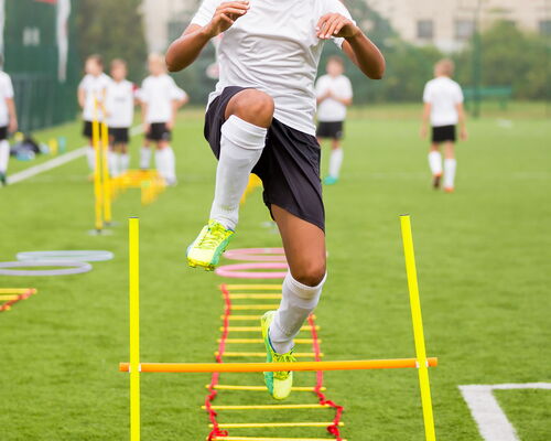 Fußballtraining. Spieler läuft über Hürde
